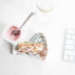 A stylish flat lay of yogurt and granola bar on a desk, perfect for a quick healthy snack.